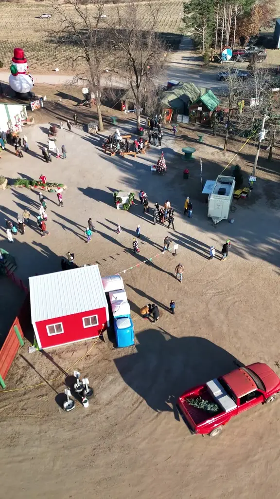 Aerial view of the farm yard on an event weekend, the giant snowman, the red barn, families crossing the grounds
