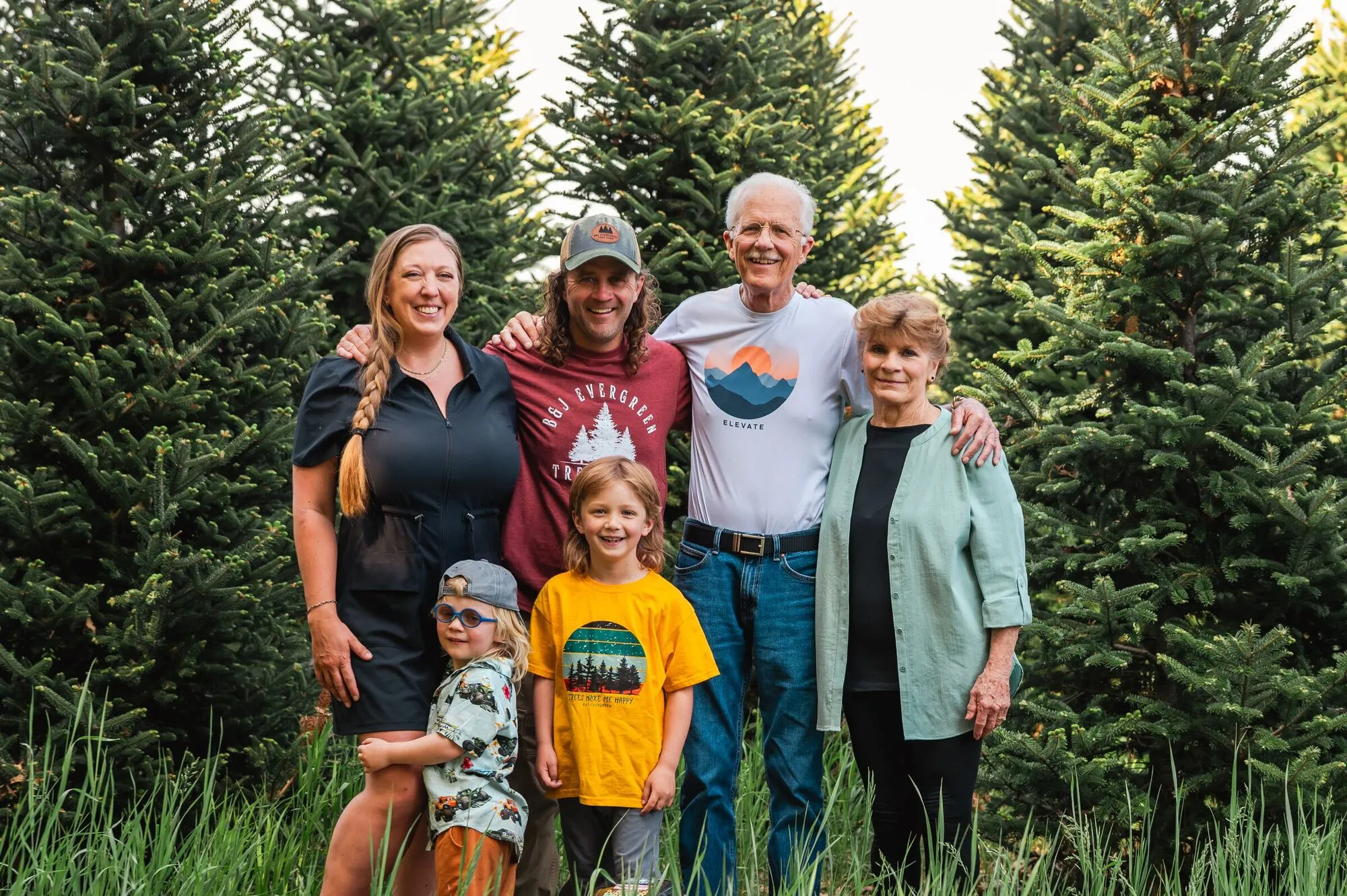 Three generations of the Johnson family standing together in front of a stand of spruce trees at the farm