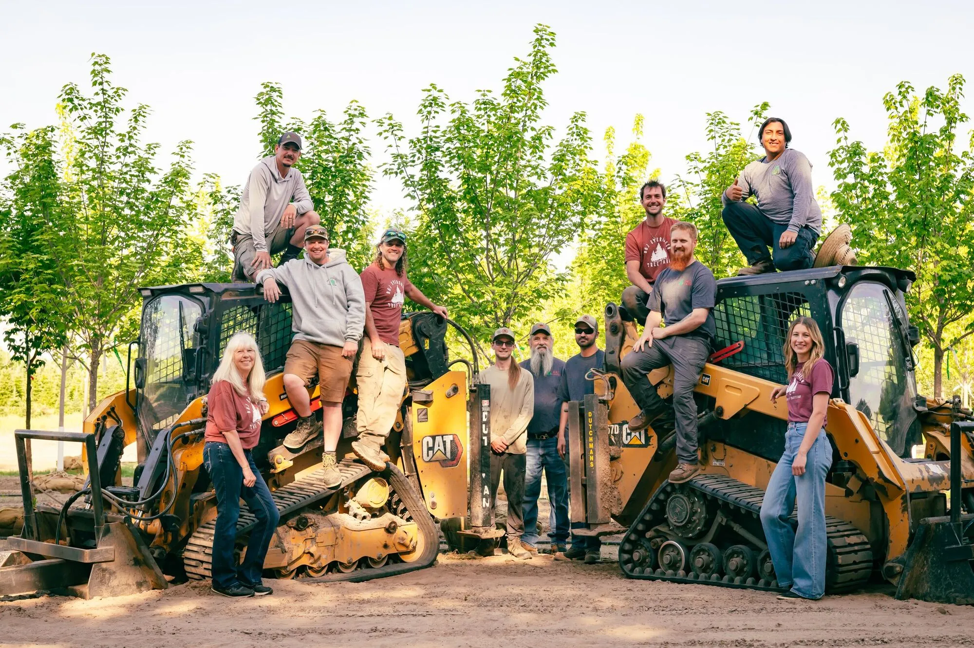 The full-time crew posed on and around two skid loaders between rows of young nursery trees